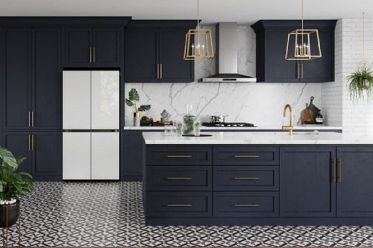 Modern kitchen with navy blue cabinets, gold hardware, white countertops, a white and black patterned floor, smart tech appliances, marble backsplash, two gold pendant lights, green plants for decoration, and a sleek white refrigerator.