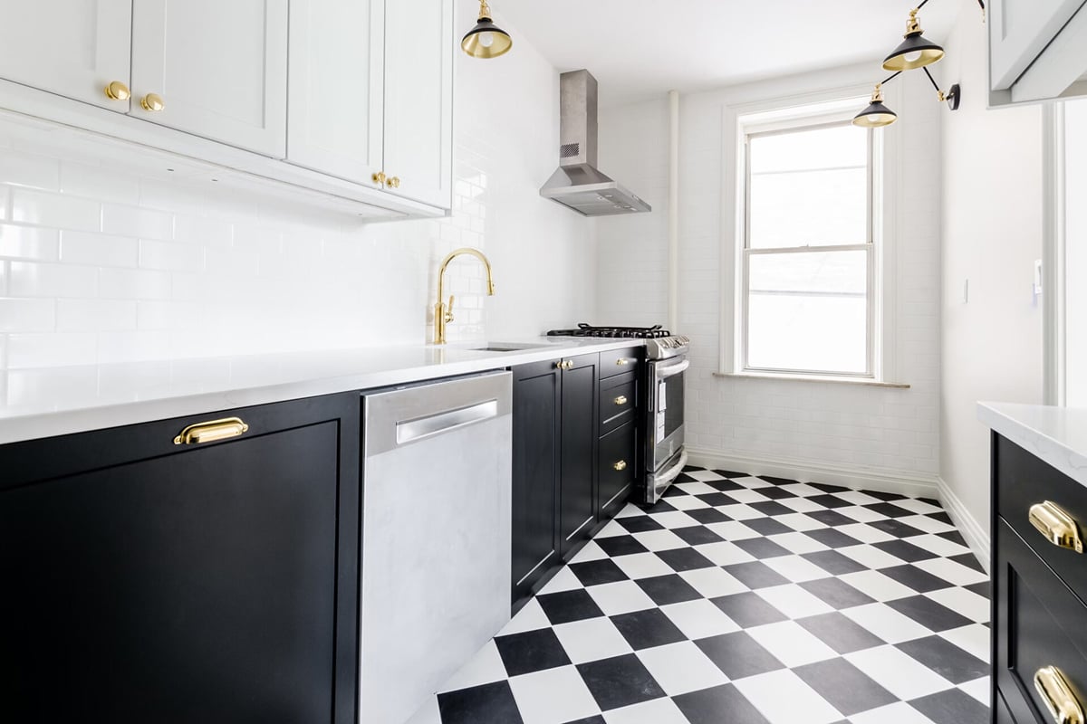 Modern kitchen design with black cabinets, gold hardware, white upper cabinets, white countertops, gold faucet, stainless steel appliances, and a black-and-white checkered tile floor. A large window lets in natural light—showcasing popular kitchen layouts. Modern kitchen design with black cabinets, gold hardware, white upper cabinets, white countertops, gold faucet, stainless steel appliances, and a black-and-white checkered tile floor. A large window lets in natural light—showcasing popular kitchen layouts.