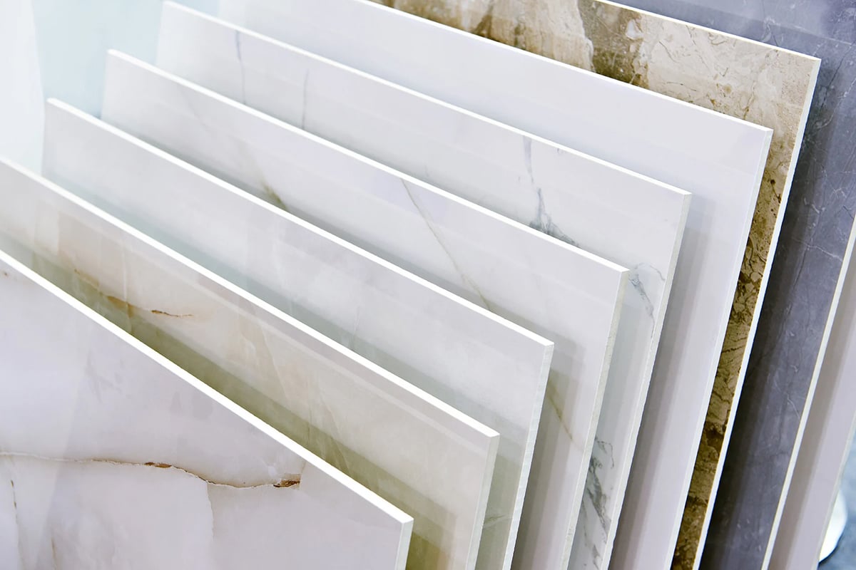 Several large rectangular slabs of tile or stone are displayed upright in a row, showcasing various shades and marble-like patterns—perfect examples of stylish water resistant flooring for any space. Several large rectangular slabs of tile or stone are displayed upright in a row, showcasing various shades and marble-like patterns—perfect examples of stylish water resistant flooring for any space.