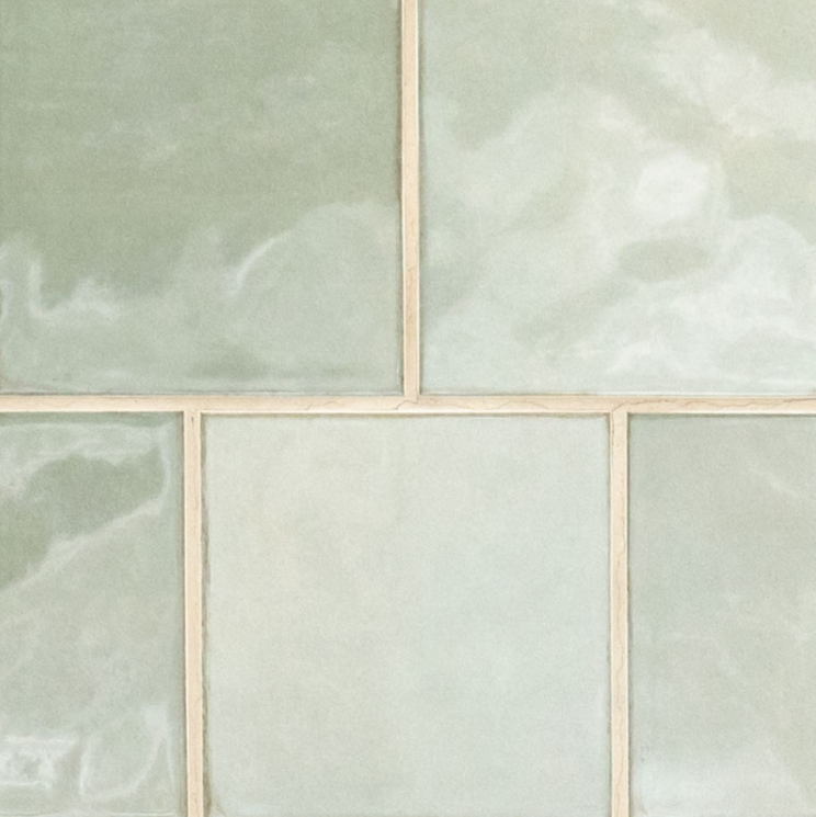 A close-up of six pale green, glossy ceramic tiles with cream-colored grout lines, arranged in a grid pattern. Perfect for a kitchen remodel, the tiles have subtle marbled textures and a soft, smooth finish. A close-up of six pale green, glossy ceramic tiles with cream-colored grout lines, arranged in a grid pattern. Perfect for a kitchen remodel, the tiles have subtle marbled textures and a soft, smooth finish.