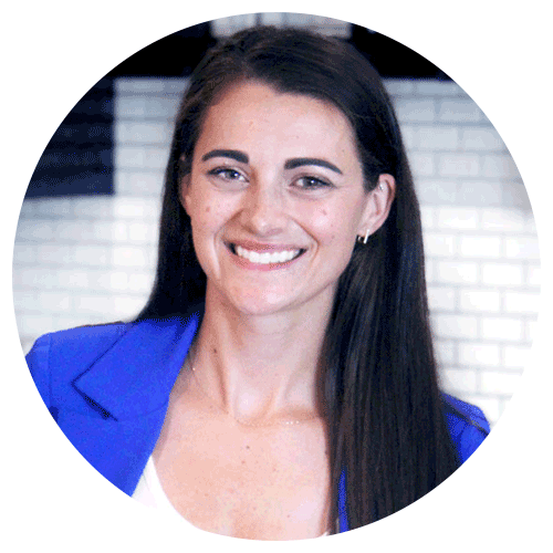 A woman with long brown hair, wearing a bright blue blazer and white top, smiles at the camera. The background features white brick tiles and dark accents from a recent kitchen remodel. A woman with long brown hair, wearing a bright blue blazer and white top, smiles at the camera. The background features white brick tiles and dark accents from a recent kitchen remodel.