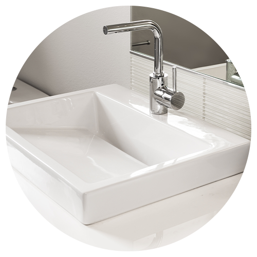 A modern white rectangular bathroom sink with a sleek chrome faucet, set on a glossy countertop in front of a striped glass backsplash and large mirror—perfect inspiration for your next kitchen remodel. A modern white rectangular bathroom sink with a sleek chrome faucet, set on a glossy countertop in front of a striped glass backsplash and large mirror—perfect inspiration for your next kitchen remodel.