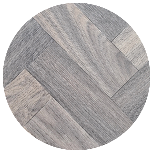 A round sample of gray wooden floor tiles arranged in a herringbone pattern, featuring various light and dark gray wood grain textures—perfect for adding style to your kitchen remodel. A round sample of gray wooden floor tiles arranged in a herringbone pattern, featuring various light and dark gray wood grain textures—perfect for adding style to your kitchen remodel.