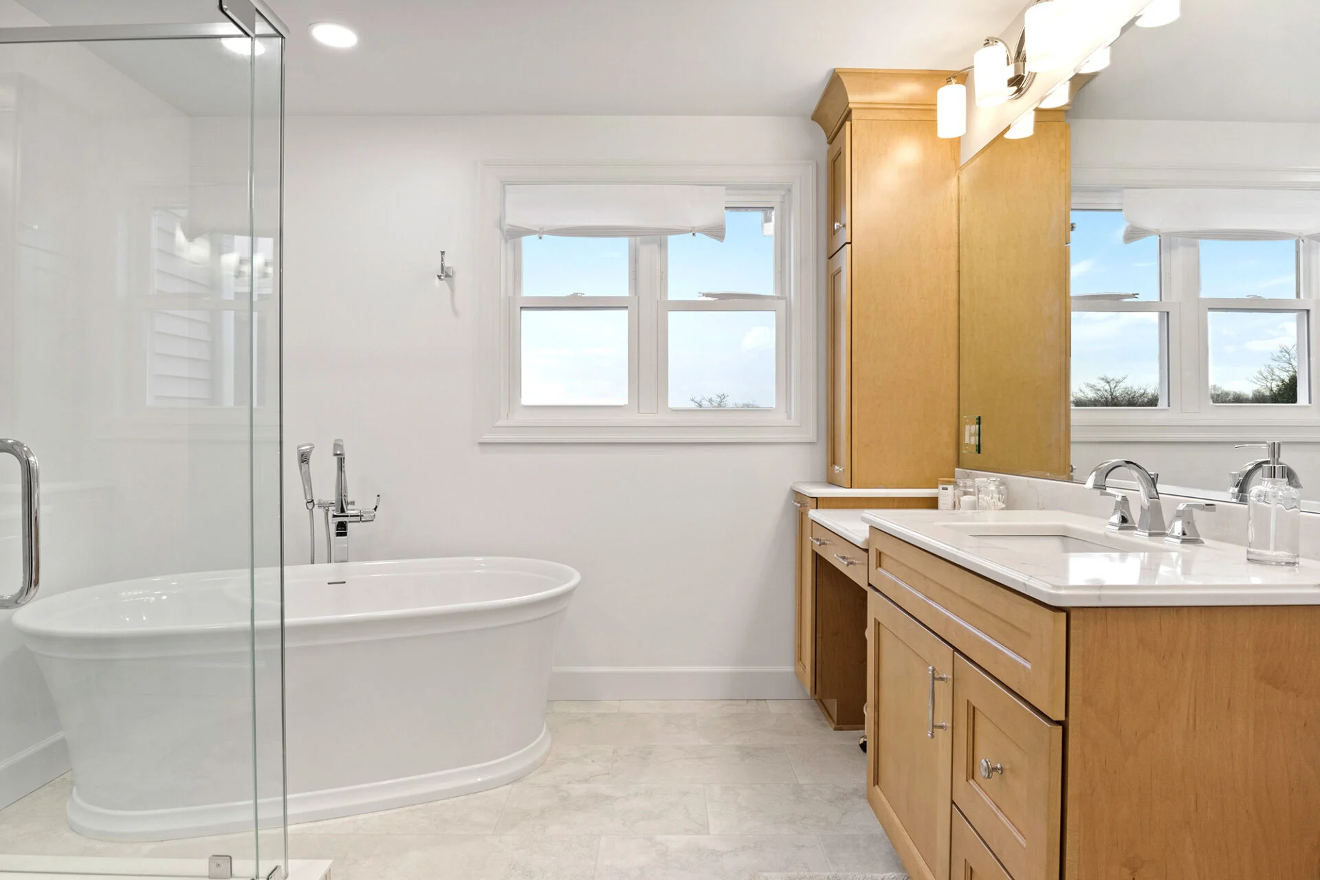Modern bathroom with a freestanding white bathtub, glass shower enclosure, large mirror, and double-sink vanity with light wood cabinets—perfect inspiration for your next kitchen remodel or home upgrade. Modern bathroom with a freestanding white bathtub, glass shower enclosure, large mirror, and double-sink vanity with light wood cabinets—perfect inspiration for your next kitchen remodel or home upgrade.