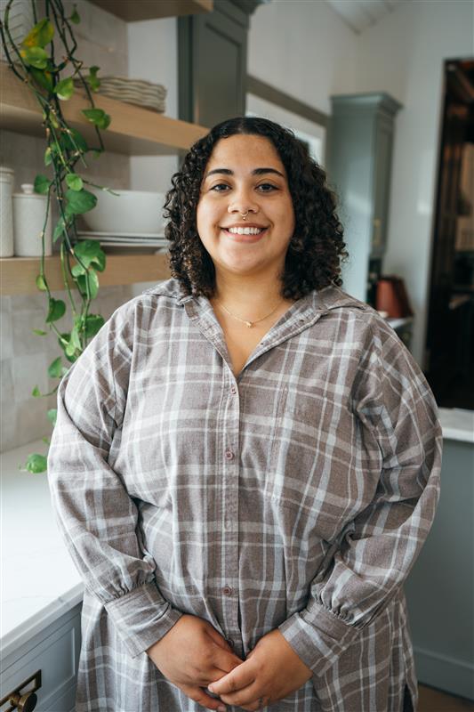 Woman with curly hair and a plaid shirt smiling