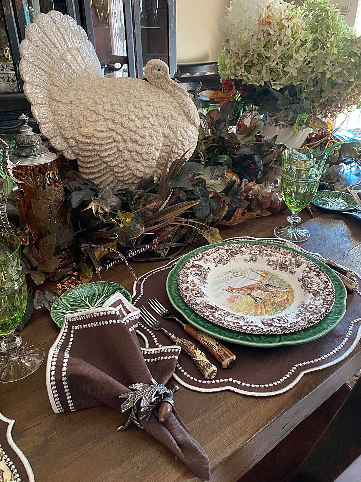 A decorative turkey centerpiece on a Thanksgiving table setting. The table is set with a brown placemat, plate, and napkin.