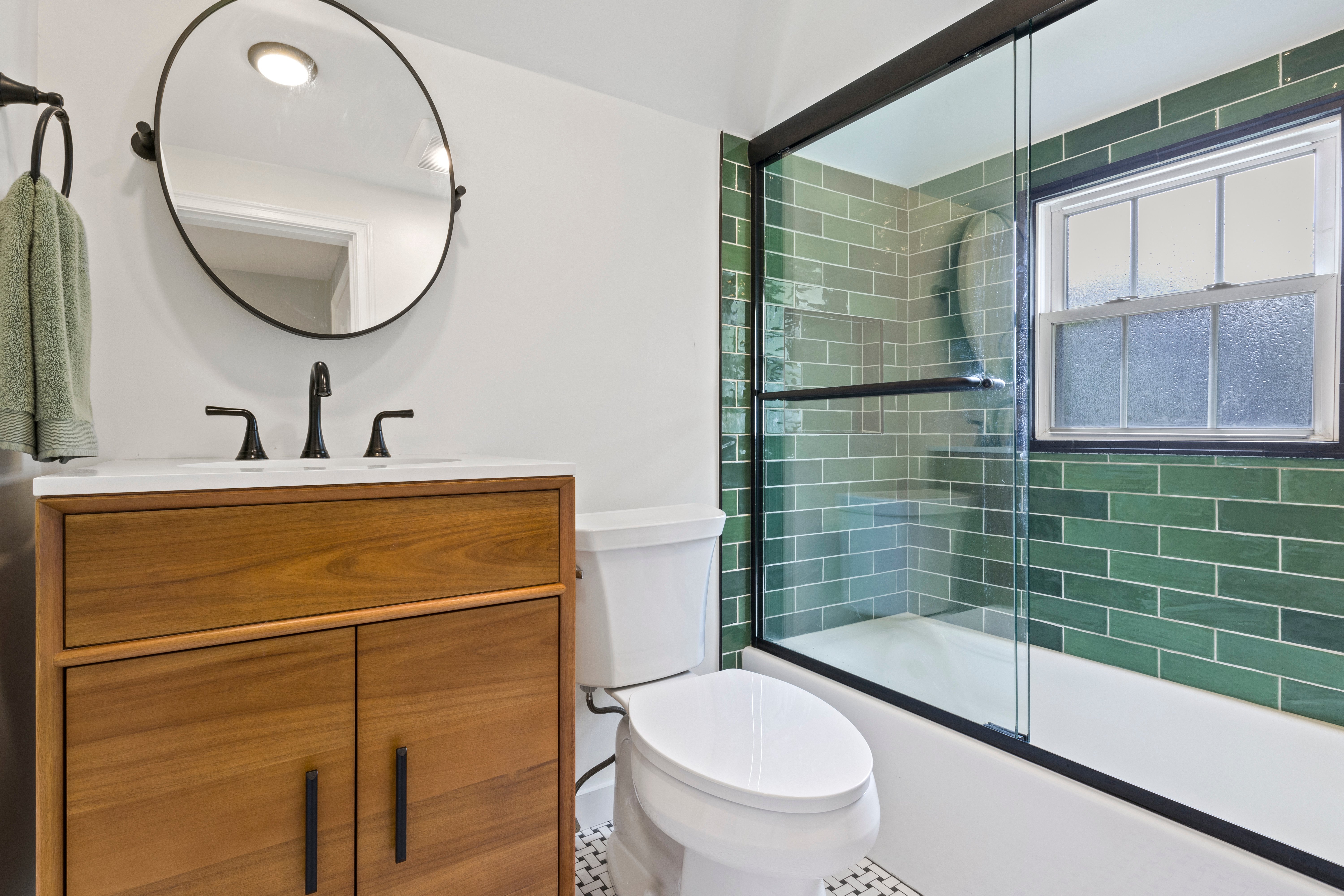 Modern bathroom interior with green tile shower and wooden vanity