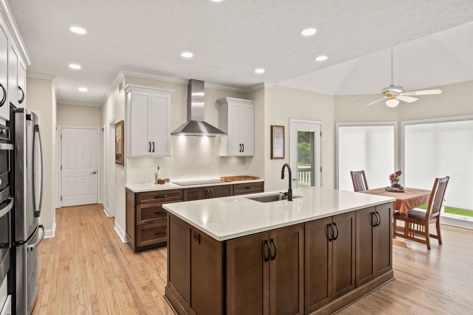 Kitchen with white countertops and dark wood cabinets. Dining area with table and chairs.
