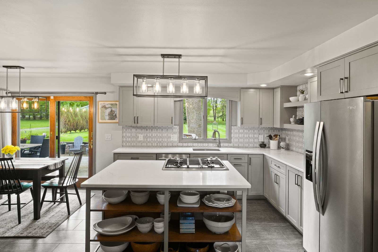 A modern kitchen with white cabinets and a large island. The kitchen features stainless steel appliances and a dining area.