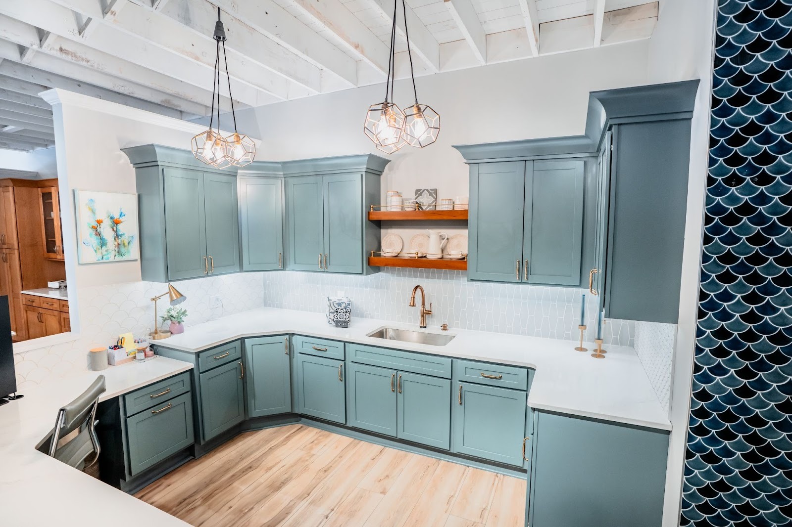 A kitchen with blue cabinets and white countertops. The room is well lit.