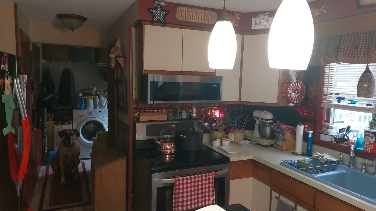 A kitchen with white cabinets and a black stove. The kitchen has a white countertop and a sink.