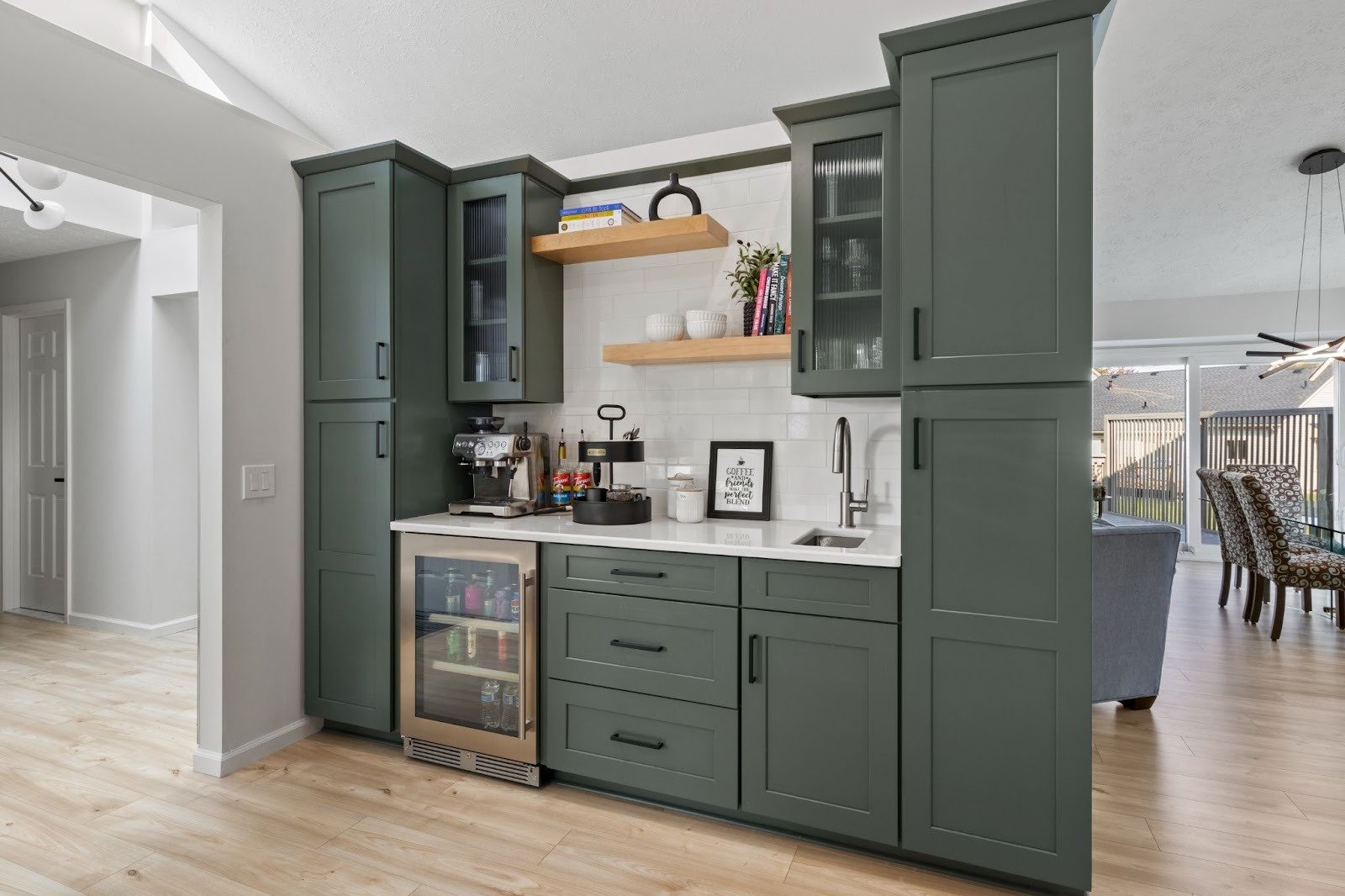 Green kitchen cabinets with white countertops and wine fridge