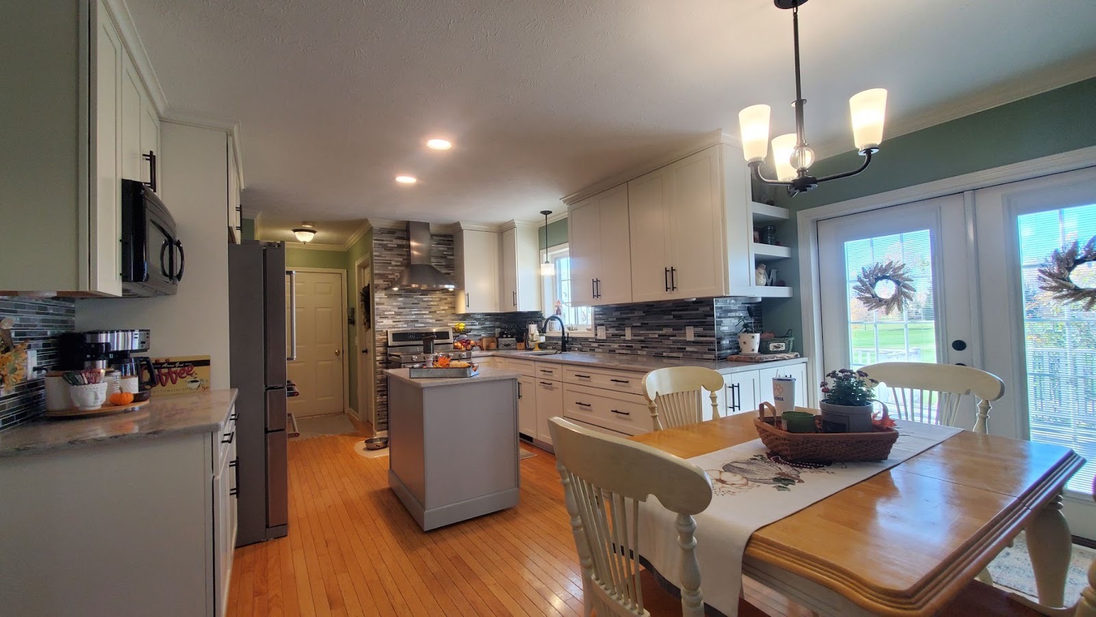 A kitchen with white cabinets and a dining table with white chairs.