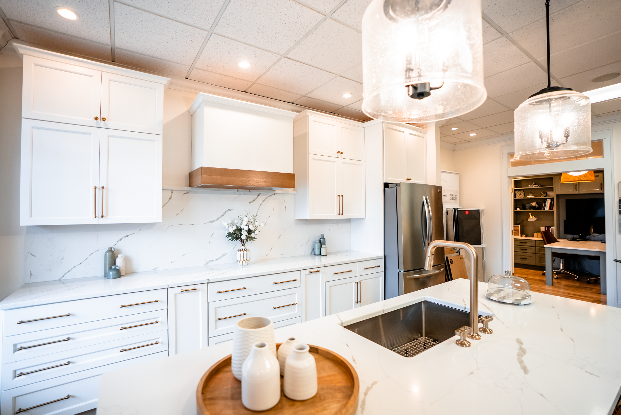 Modern kitchen interior with white cabinets and appliances. Kitchen island with marble countertop and sink.