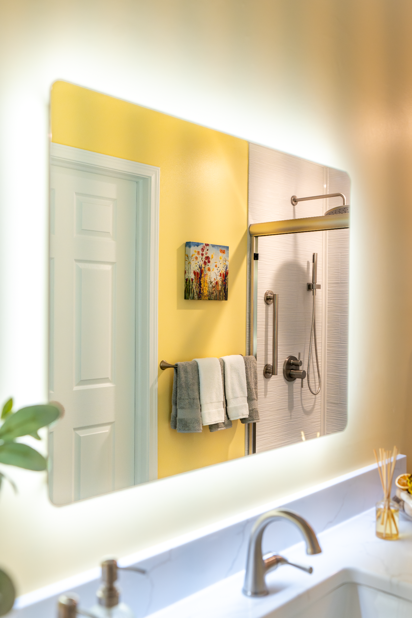 A bathroom mirror with LED light and reflection of shower area. The mirror is mounted above a sink.