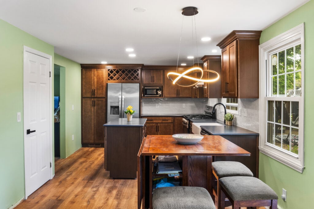 A kitchen with wooden cabinets and island. A dining area with a table and stools.