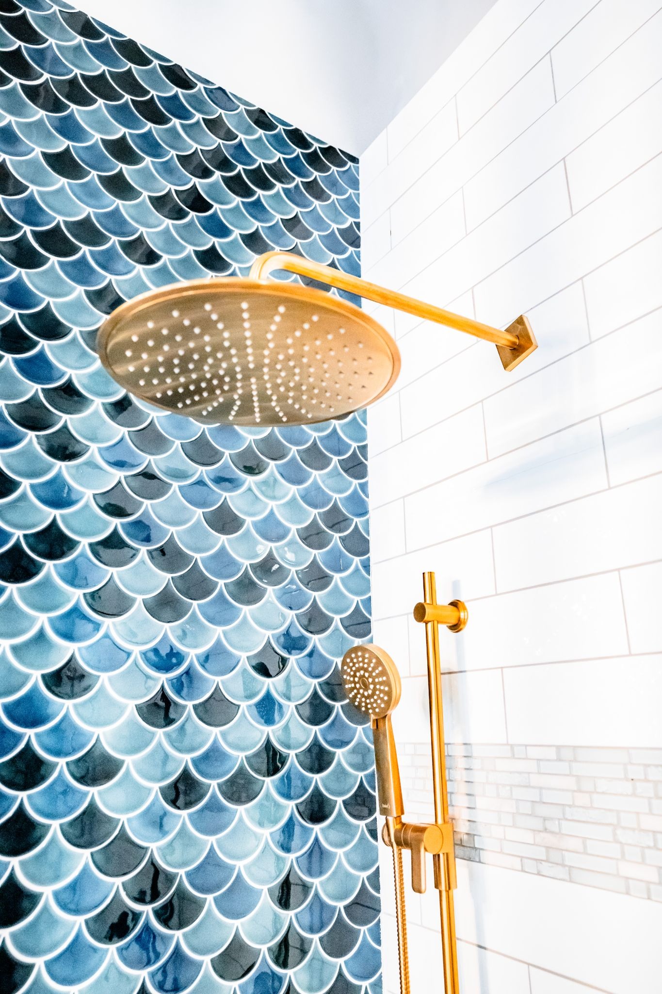A gold shower head and handle against blue and white tiles.