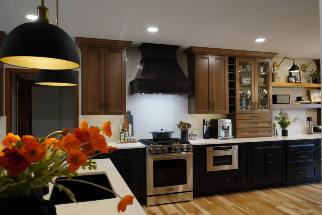 Modern kitchen interior with black and wood cabinets and orange flowers on the counter.