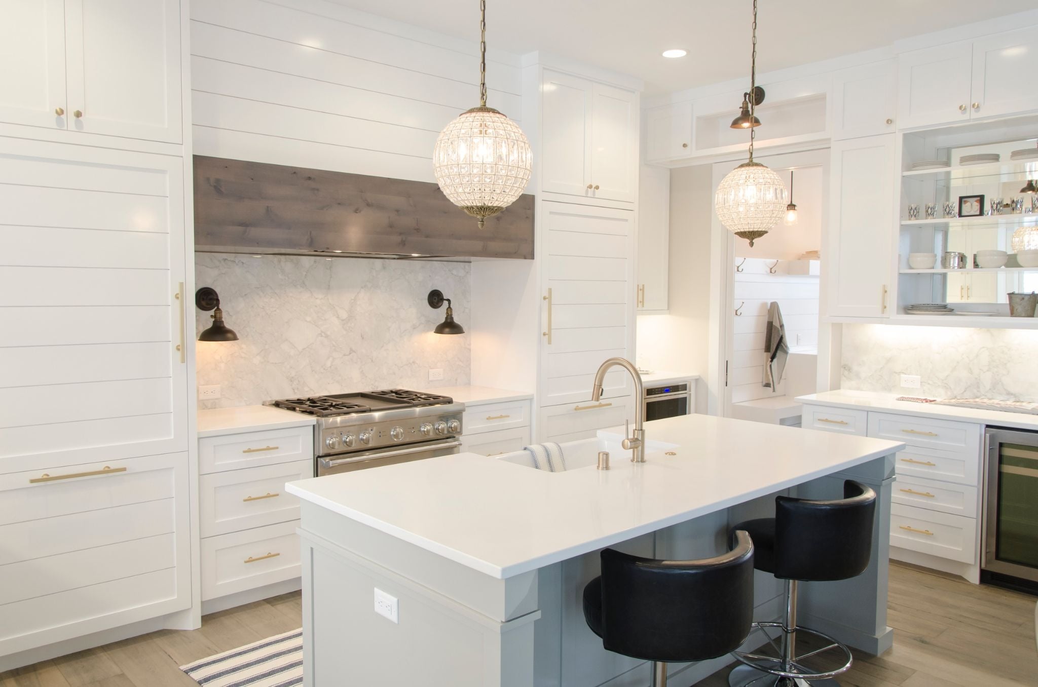 Modern kitchen with white cabinets and island. Black barstools at the island.