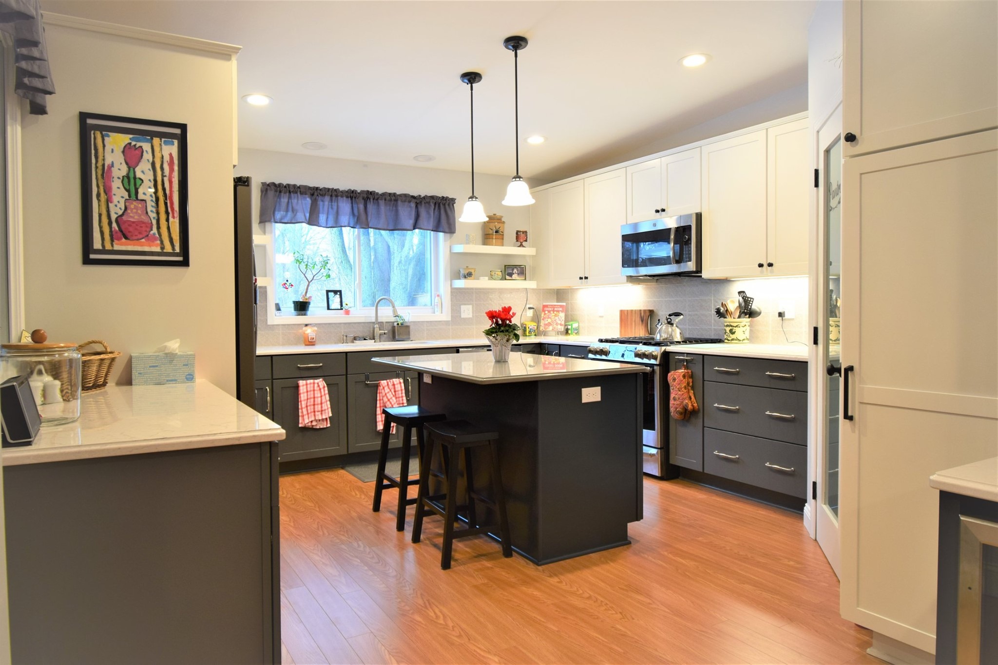 A kitchen with a large island and pendant lights. The kitchen is well-lit and features modern appliances.