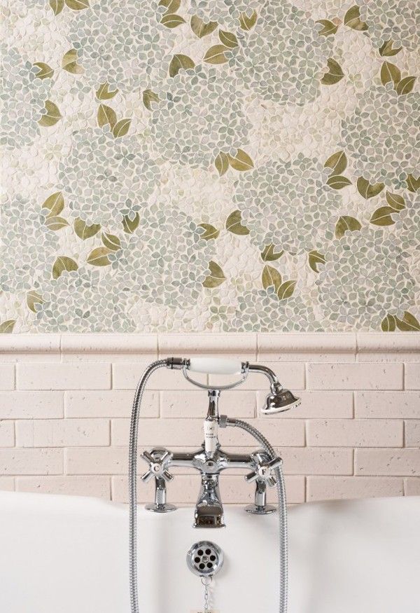 A bathtub with a silver faucet and shower head, floral wallpaper