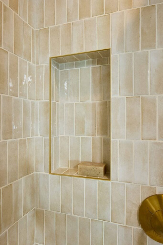 Tiled shower alcove with beige stone tiles. Shower recess.
