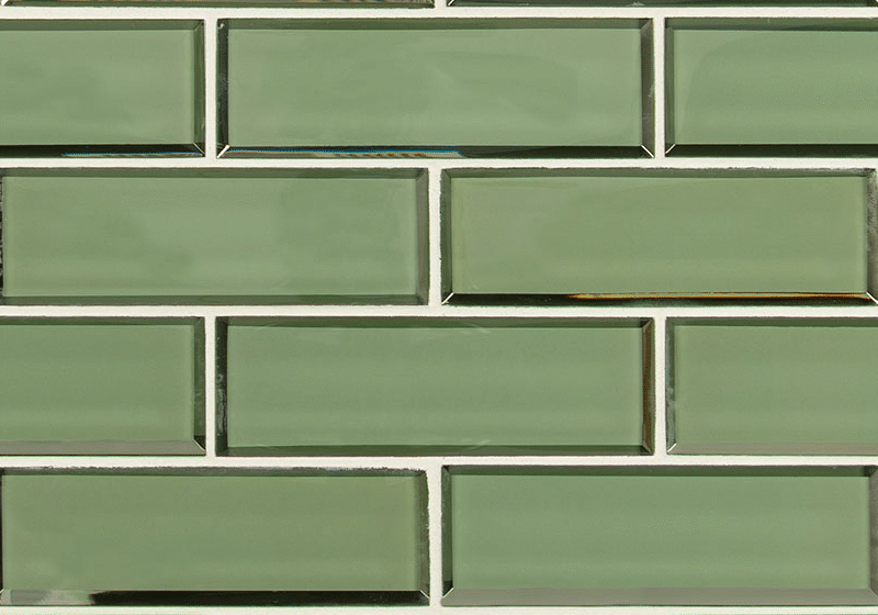 A close-up of a wall covered with glossy, rectangular green tiles arranged in a horizontal brick pattern with white grout lines, perfect for a stylish kitchen remodel.