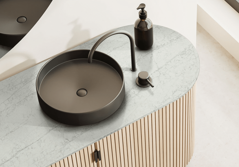 A modern bathroom sink with a round black basin, matching faucet, soap dispenser, and lever sits on a light marble countertop above a wood slat cabinet—perfect inspiration for your next kitchen remodel.