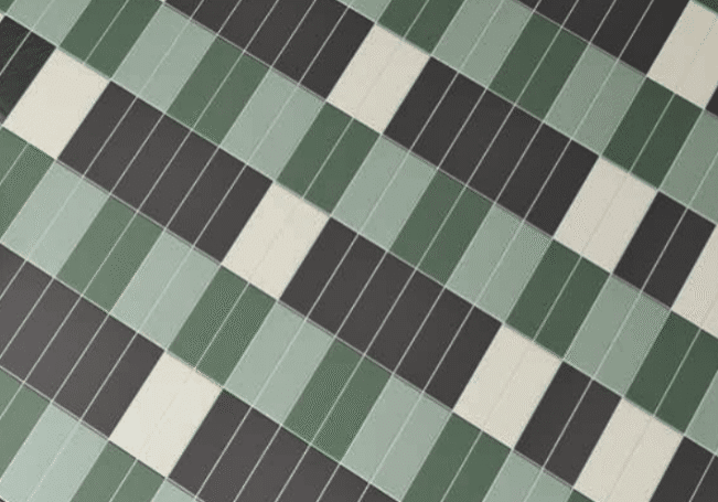 A close-up of a tiled surface, perfect for a kitchen remodel, featuring a diagonal pattern of rectangles in dark green, light green, black, and white, arranged in alternating, staggered rows.