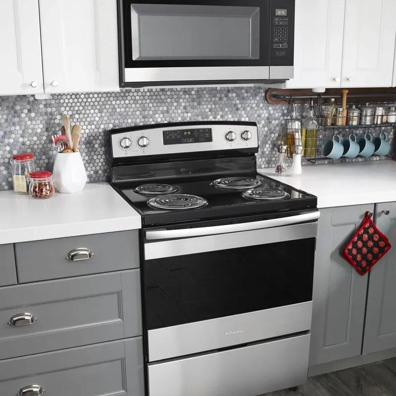 A modern kitchen with a stove, microwave, and white countertops. The kitchen has gray cabinets and a gray tile backsplash.