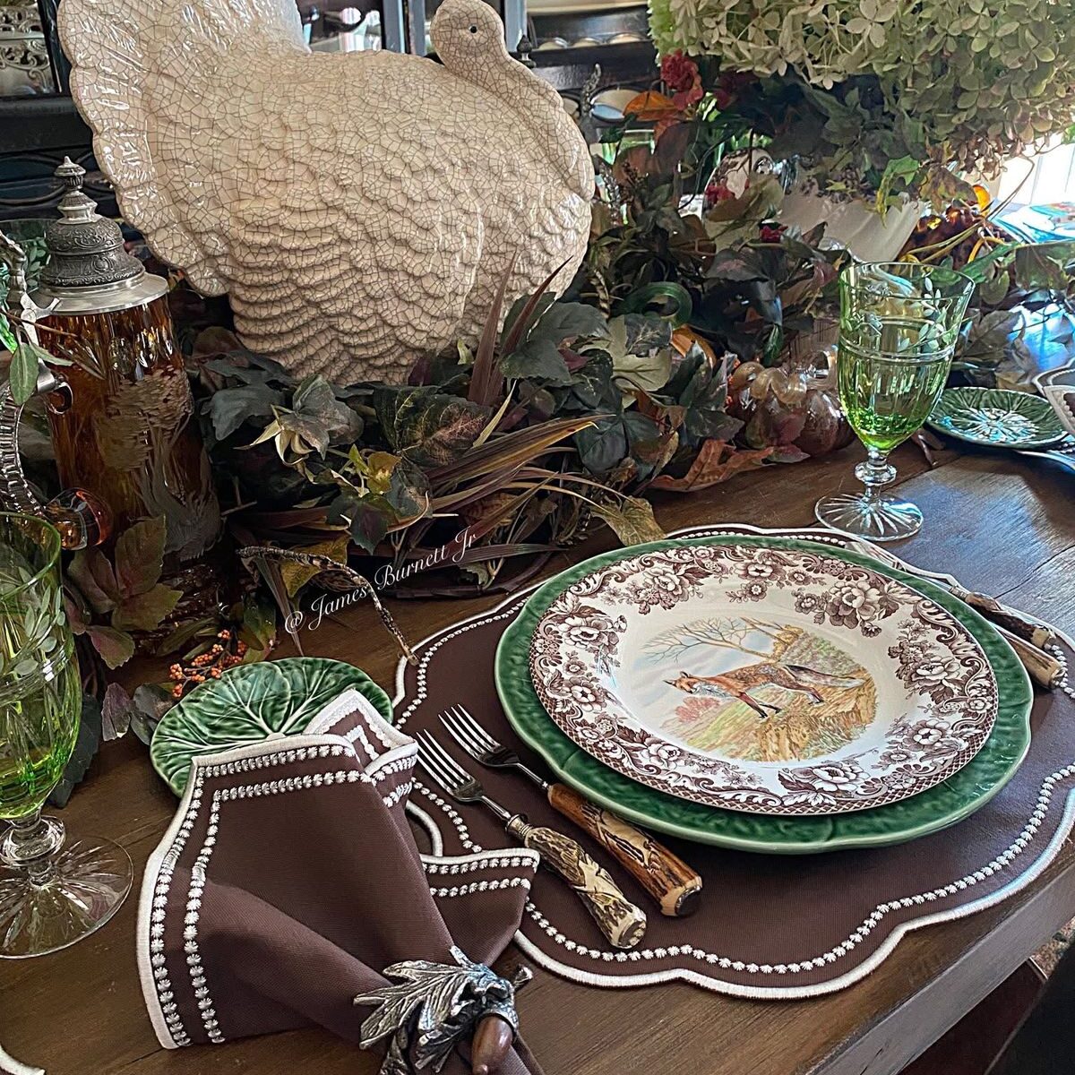 A decorative turkey centerpiece on a Thanksgiving table setting. The table is set with a brown placemat, plate, and napkin.